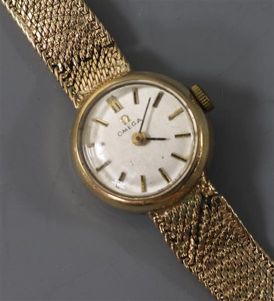 A ladys 9ct gold Omega manual wind wrist watch with an integral 9ct gold bracelet.